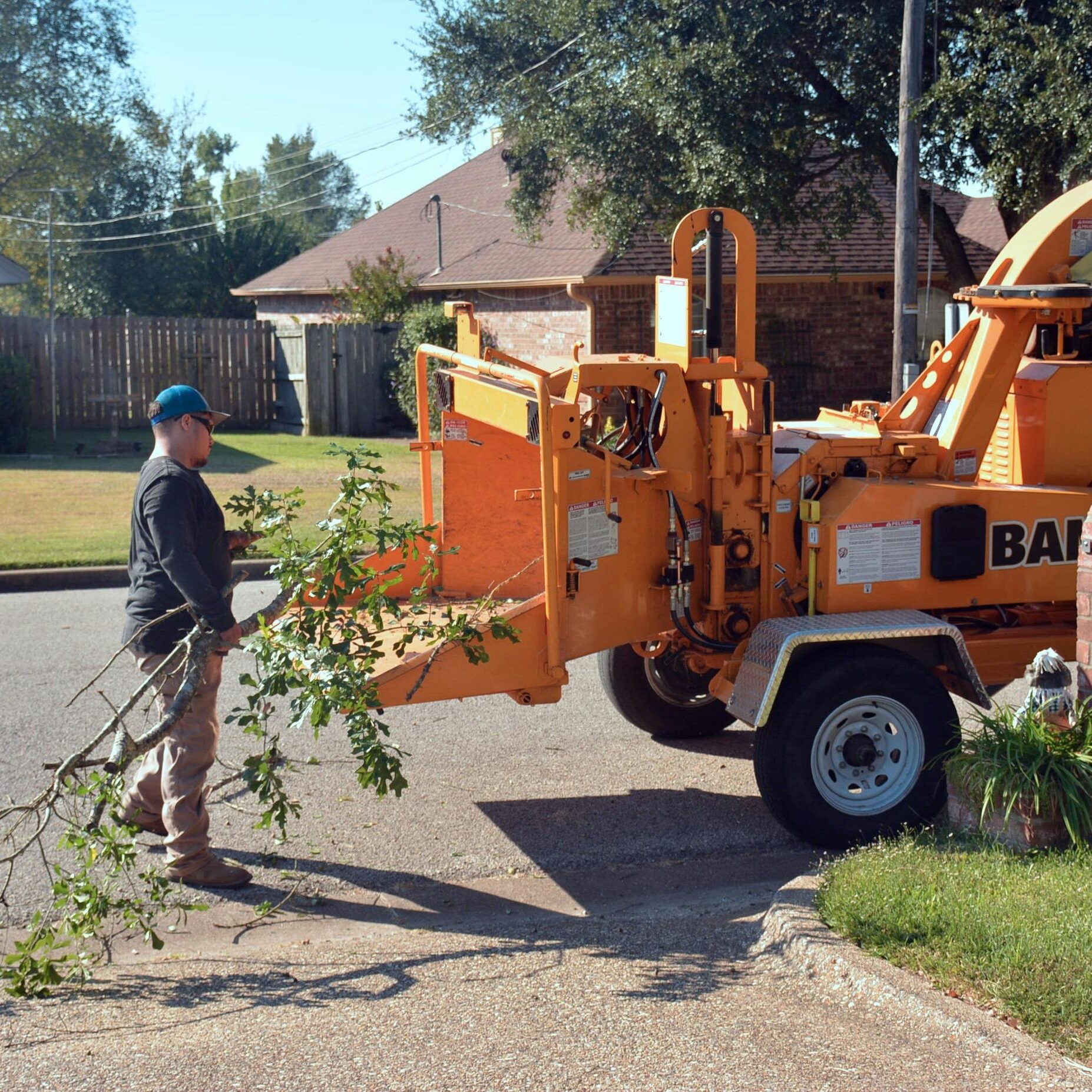 pexels-photo-34581908-34581908 A person operates a wood chipper to trim and manage tree branches outdoors.